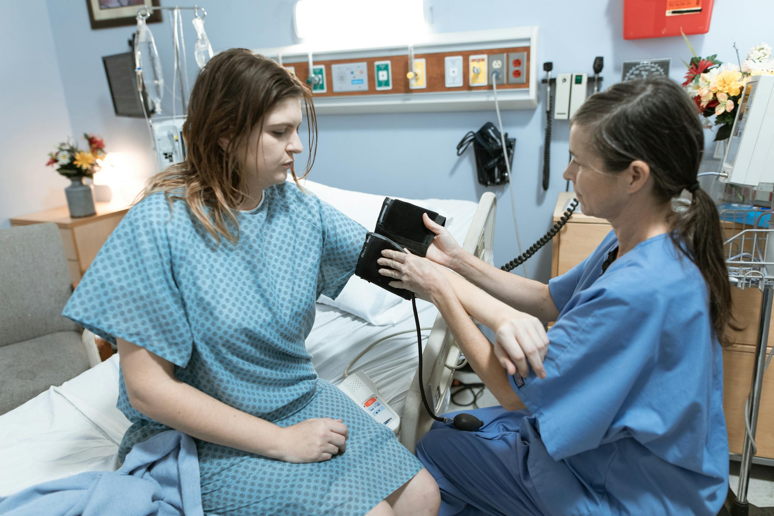 A nurse measures a patient's blood pressure in a hospital room, focusing on healthcare and medical care.